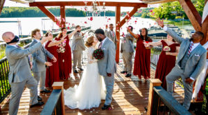 Bride and Groom kissing while bridal party throws roses at the couple